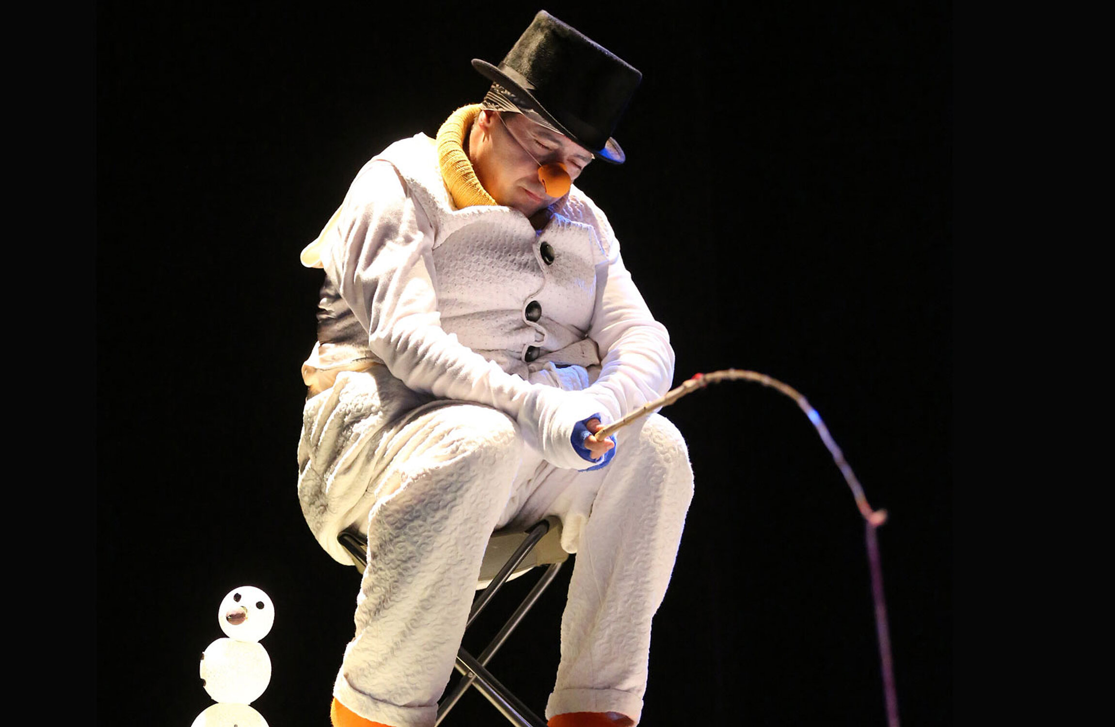 Schauspieler im Schneemannkostüm sitzt mit einer Angel gekrümmt