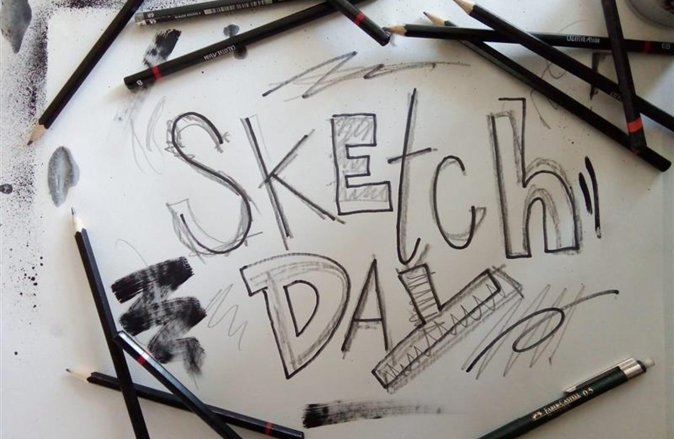 Skizze des Schriftzugs SKETCH DAY auf weißem Papier umgeben von verschiedenen Stiften.