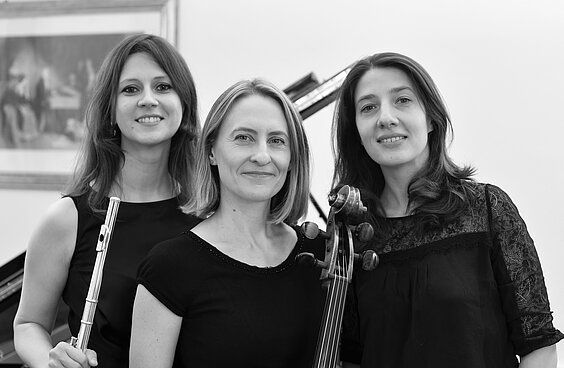 Drei Musikerinnen Anna Mazurek (Cello), Liudmyla Polova (Klavier) und Maruta Staravoitava (Floete) vor einem Flügel stehend