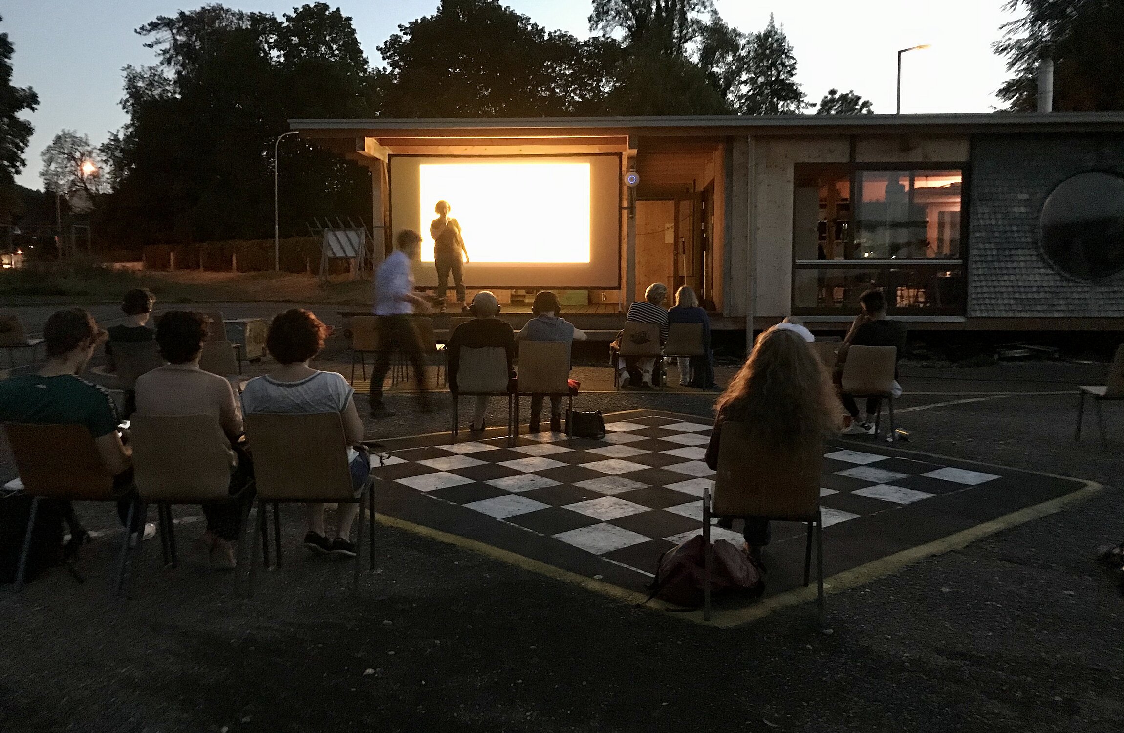Open-Air Kino mit Publikum vor einer Leinwand im Freien