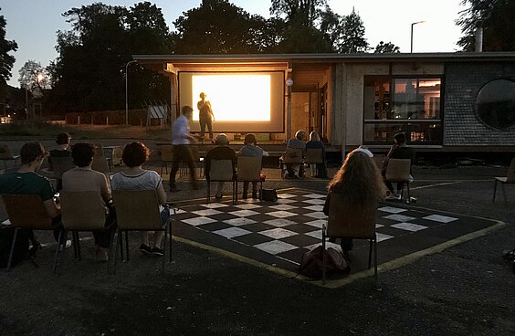 Open-Air Kino mit Publikum vor einer Leinwand im Freien