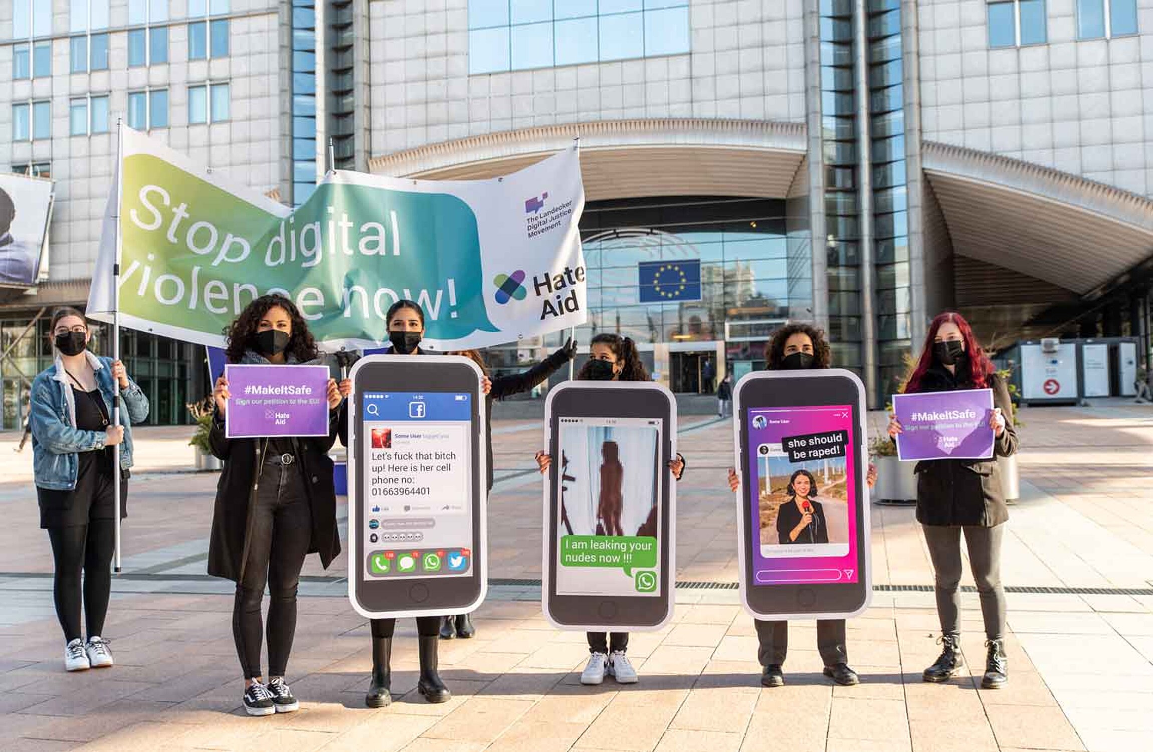 Gegen digitale Gewalt protestierende Frauen mit Schildern in Form von Smartphones mit Hate Sprach-Aufschrift vor dem Europäischen Parlament in Brüssel
